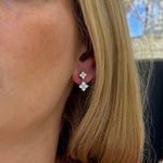 A close-up of a woman's ear wearing a 14k white gold diamond drop earrings with a clover design