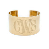 Gold cuff bracelet with engraved initials on a white background