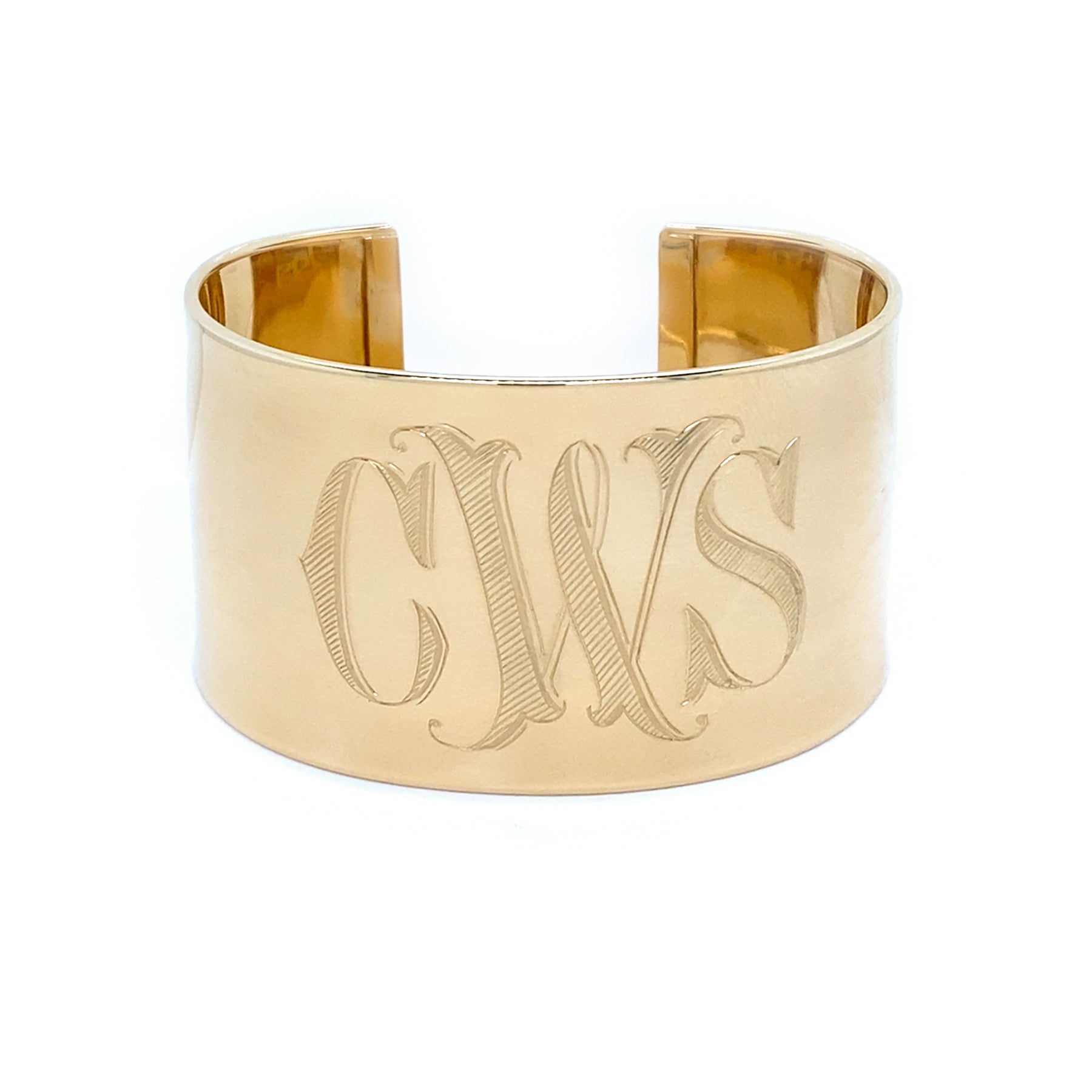Gold cuff bracelet with engraved initials on a white background