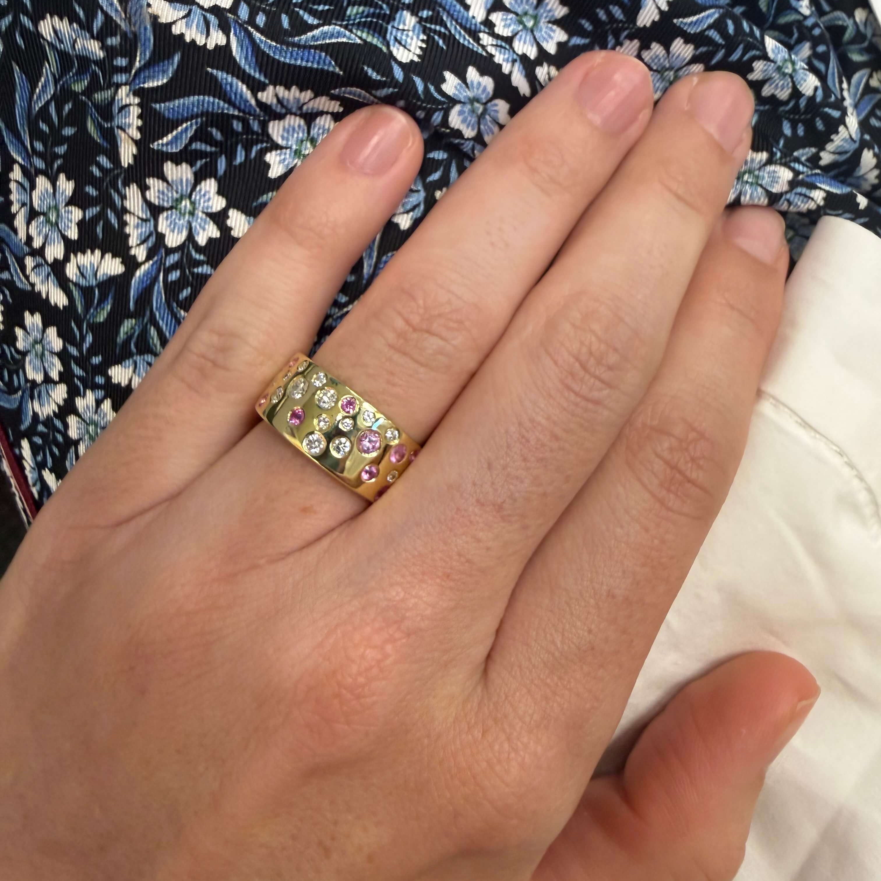 Hand wearing a gold pink sapphire and diamond ring