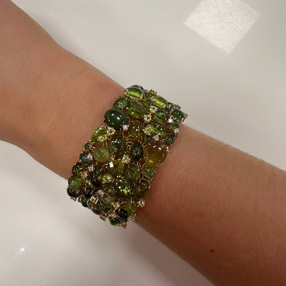 Green Peridot bracelet on a wrist against a neutral background