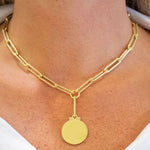 18K Gold chain necklace with a round pendant on a woman wearing a white top.
