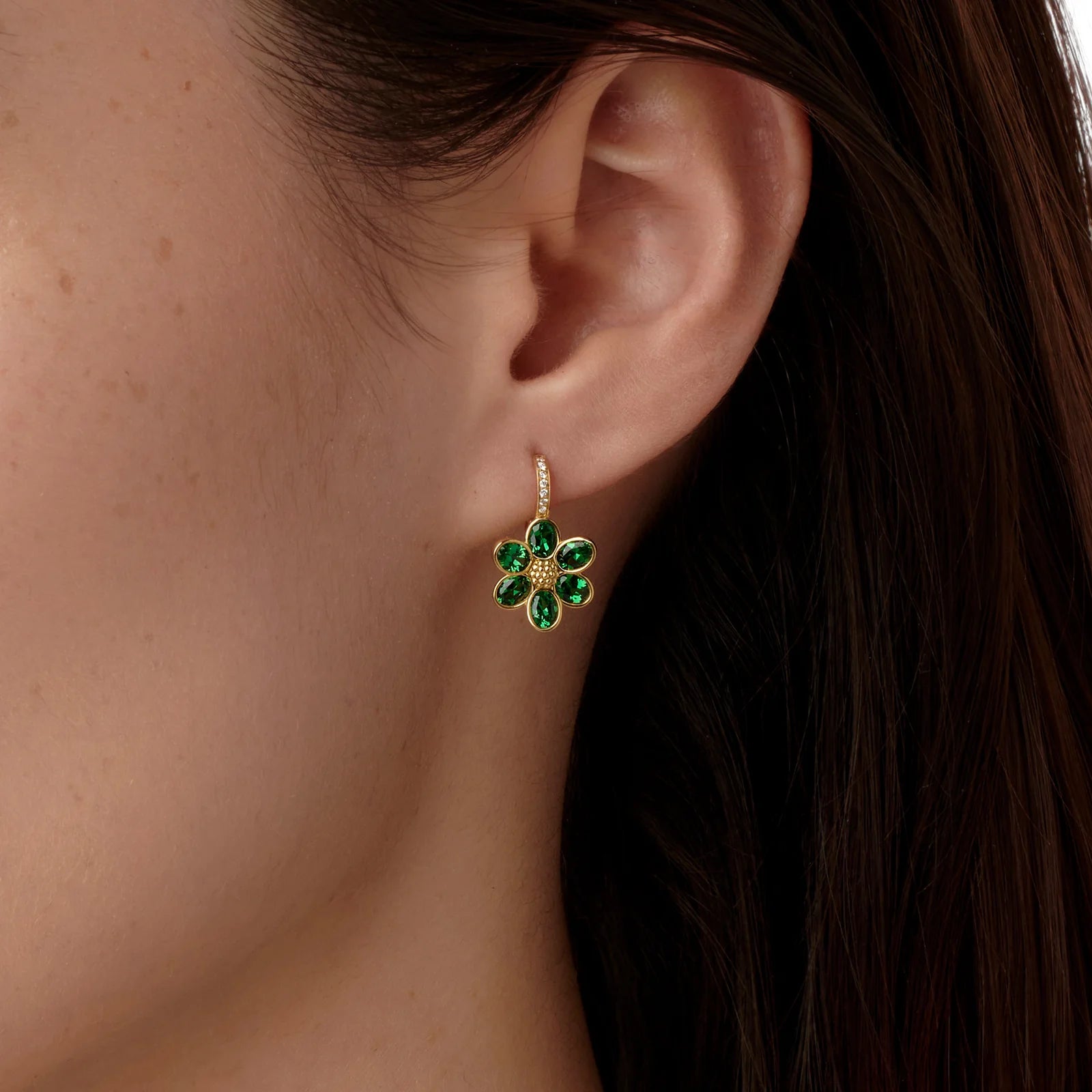 Close-up of a woman wearing a green tsavorite earring with diamonds in 18K gold designed by Elizabeth Locke