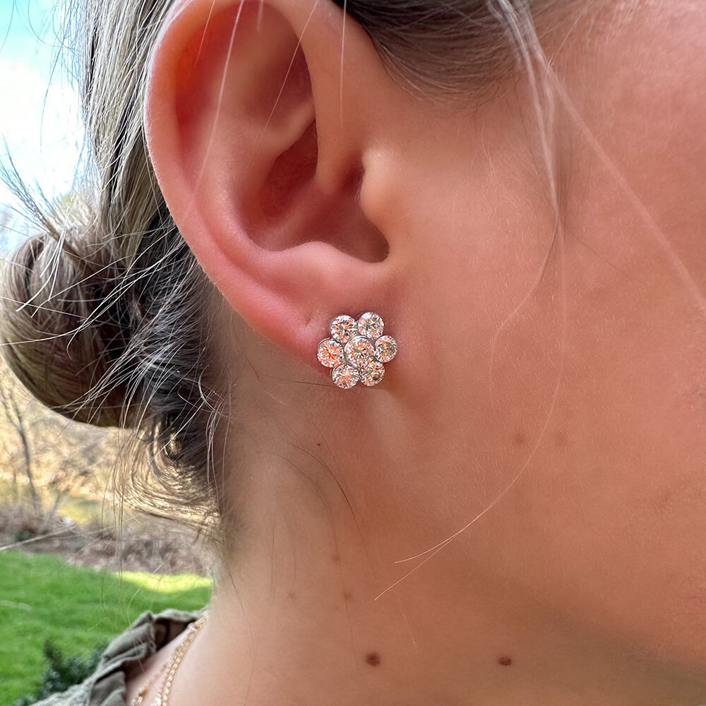 A close-up of a woman's ear wearing an 18K white gold diamond flower earring stud earring 