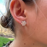 A close-up of a woman's ear wearing an 18K white gold diamond flower earring stud earring 