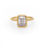 An 18K yellow gold emerald-cut diamond bezel ring
