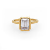 An 18K yellow gold emerald-cut diamond bezel ring