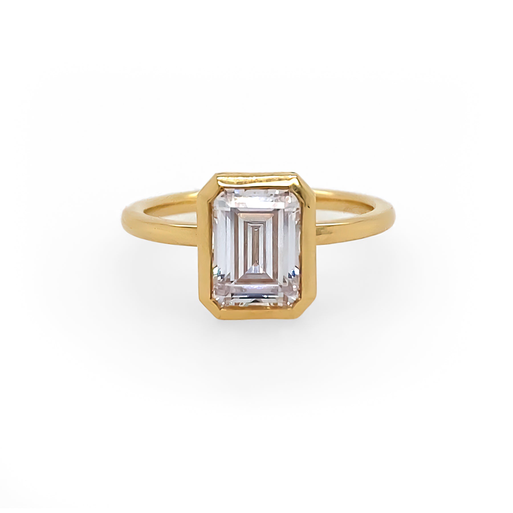An 18K yellow gold emerald-cut diamond bezel ring