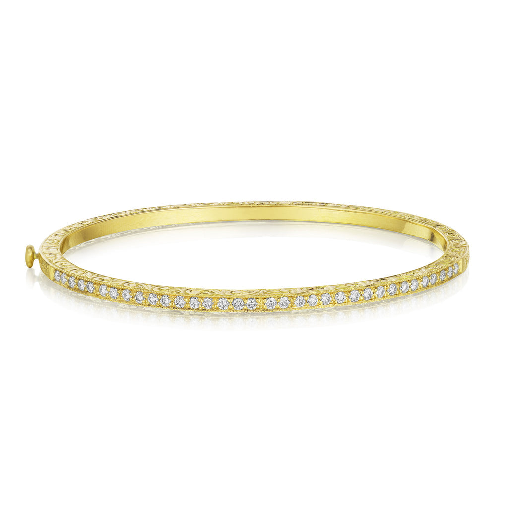 A thin yellow gold bangle bracelet encrusted with diamonds.