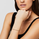 Woman wearing a gold and diamond bracelet on a neutral background