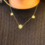 Woman wearing 18K gold small pave diamond 3 station flower necklace