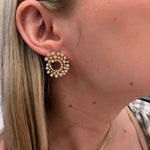 Close-up of a person wearing pearl hoop earrings with a neutral background