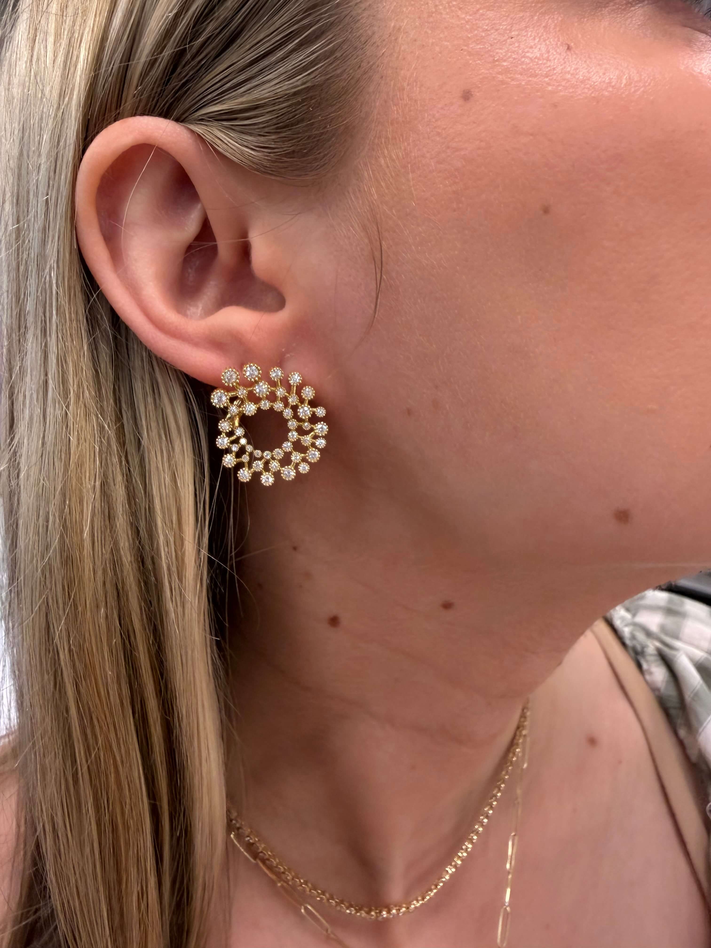 Close-up of a person wearing pearl hoop earrings with a neutral background