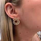 Close-up of a woman wearing 18K gold beaded bezel diamond earrings