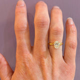 18K Gold ring with a diamond on a woman's finger against a plain background