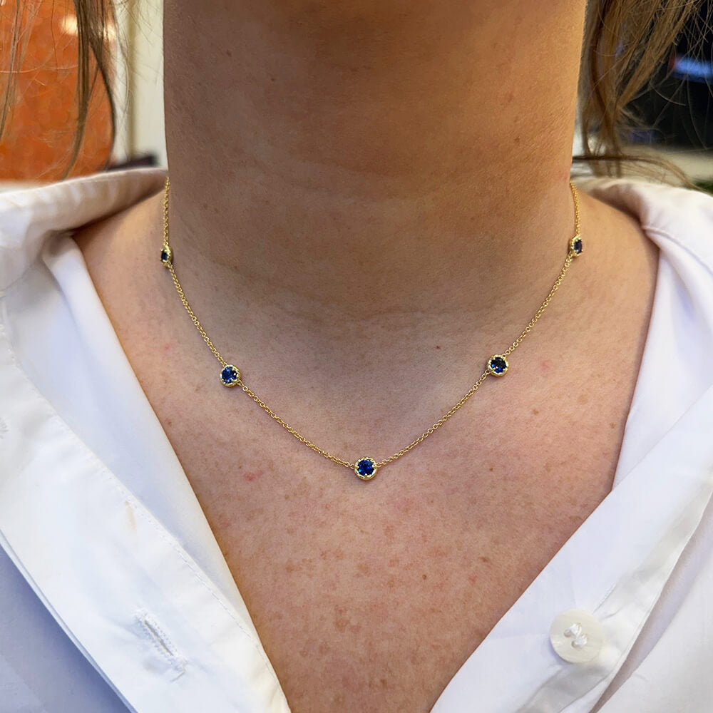 Woman wearing 18K yellow gold Sapphire 5 station necklace