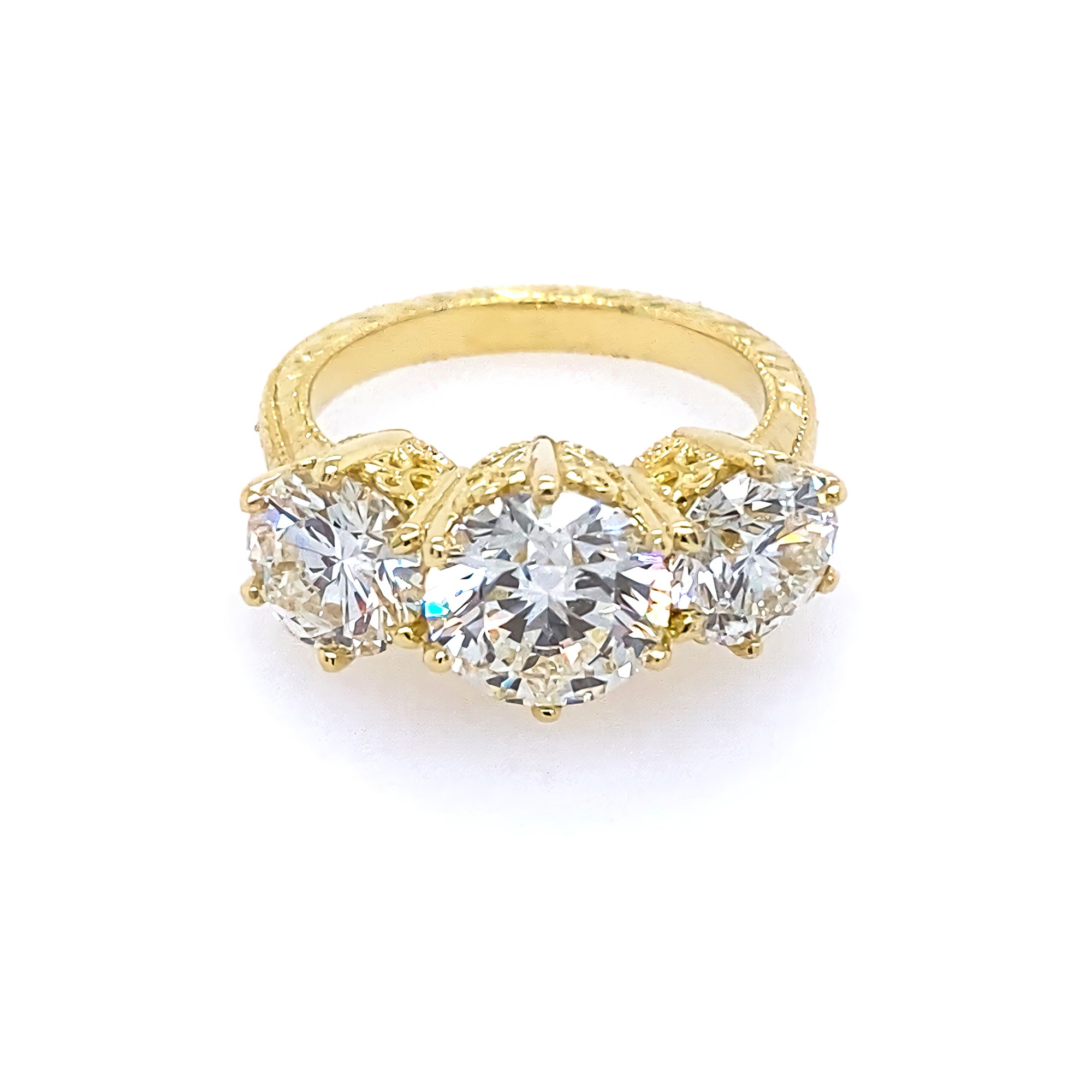 An 18kt yellow gold three-stone diamond ring with a filigree design.