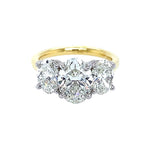 A three-stone diamond ring featuring a central oval brilliant-cut diamond flanked by two oval-cut diamonds, set in an 18K yellow gold band with platinum prongs, isolated on a white background.