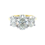 A three-stone diamond ring featuring a central oval brilliant-cut diamond flanked by two oval-cut diamonds, set in an 18K yellow gold band with platinum prongs, isolated on a white background.