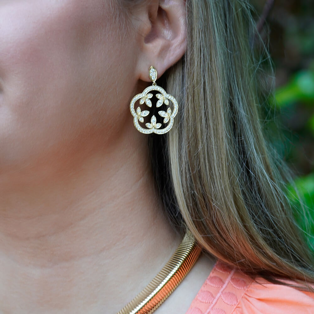 Close-up of a woman wearing an 18K gold scalloped clover earring with diamonds designed by Laura Pearce
