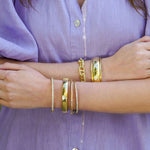 woman wearing multiple 18K gold bracelets offered by Laura Pearce Ltd.