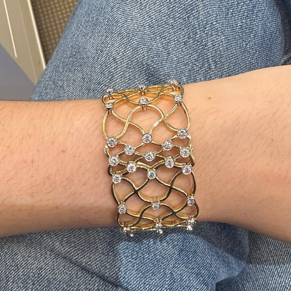18K Gold bracelet with diamond accents on a wrist against a blue denim background