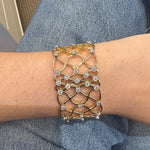 18K Gold bracelet with diamond accents on a wrist against a blue denim background