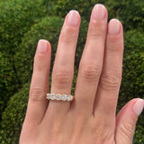Hand wearing an 18K gold diamond ring with a green background