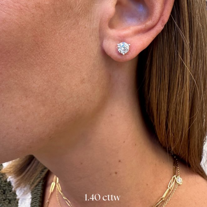 Close-up of an ear wearing a diamond earring with visible weight '1.40 cttw'.