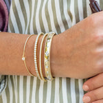 woman wearing several 18k yellow gold diamond bracelets offered by Laura Pearce Ltd.