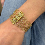 A close-up of an 18K gold multi-strand chain bracelet worn on a woman's wrist, 