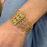 A close-up of an 18K gold multi-strand chain bracelet worn on a woman's wrist, 