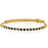 A yellow gold bangle bracelet featuring a row of round-cut deep blue sapphires, displayed on a clean white background.