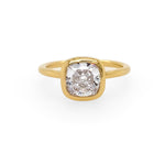 An 18K yellow gold bezel ring with a large square-cut diamond in the center.