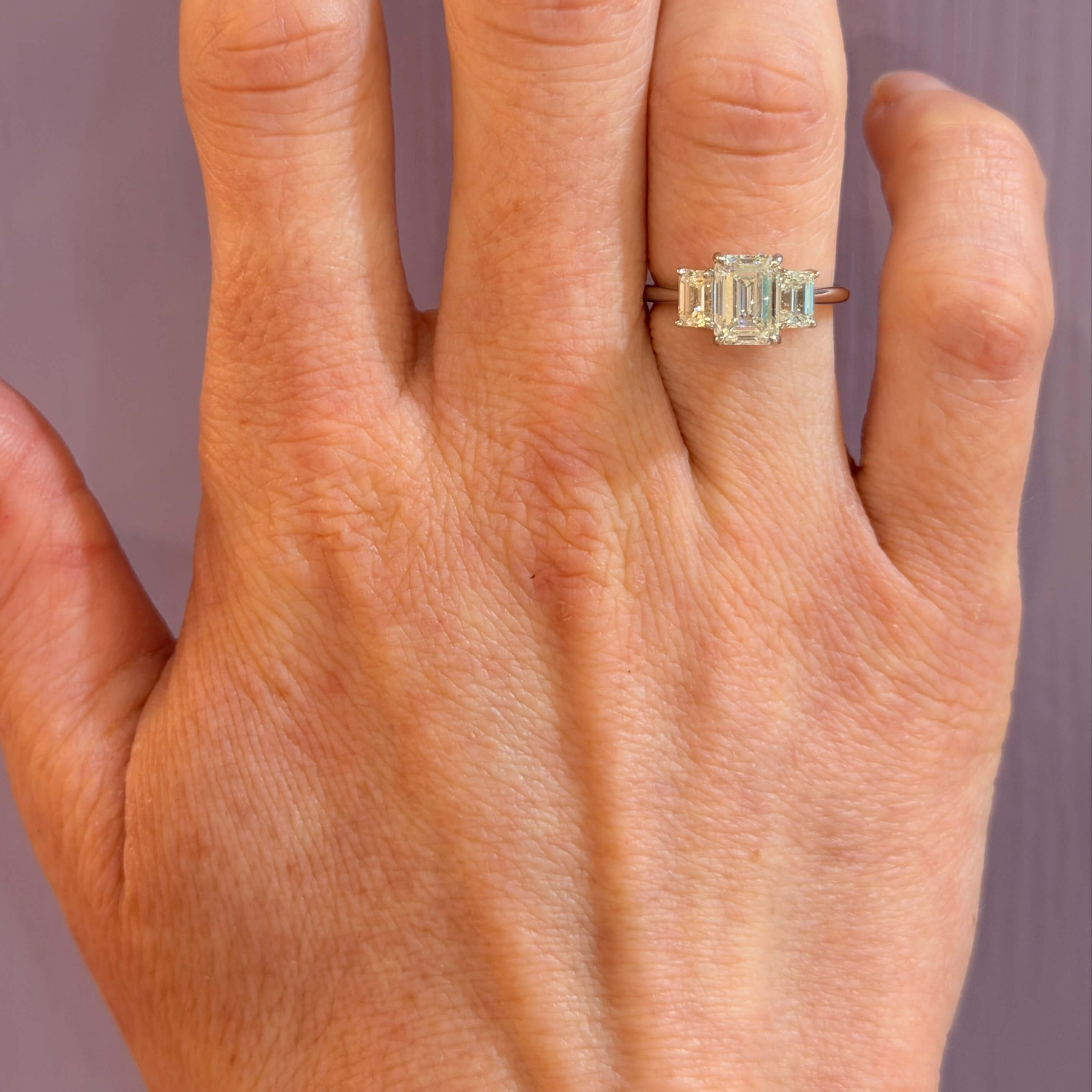 woman wearing 18K white gold emerald cut 3 stone diamond ring