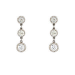 A pair of 18K white gold drop earrings, each featuring three graduated round-cut clear diamonds, shown against a plain white background.