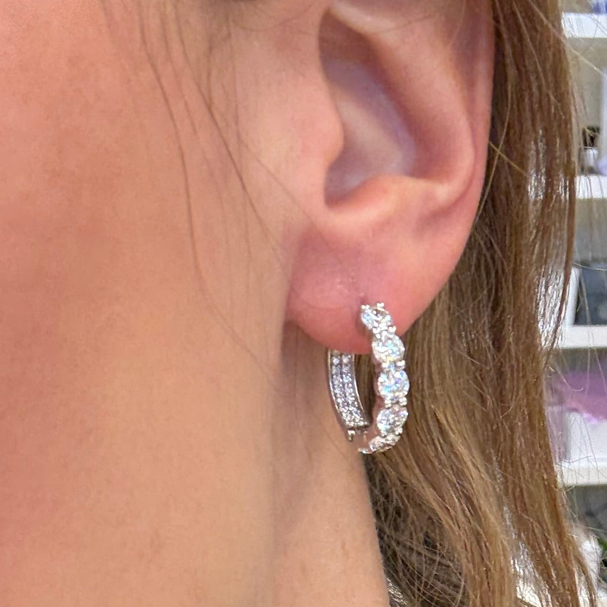 Close-up of a woman wearing diamond hoop earrings.