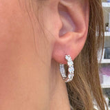 Close-up of a woman wearing diamond hoop earrings.
