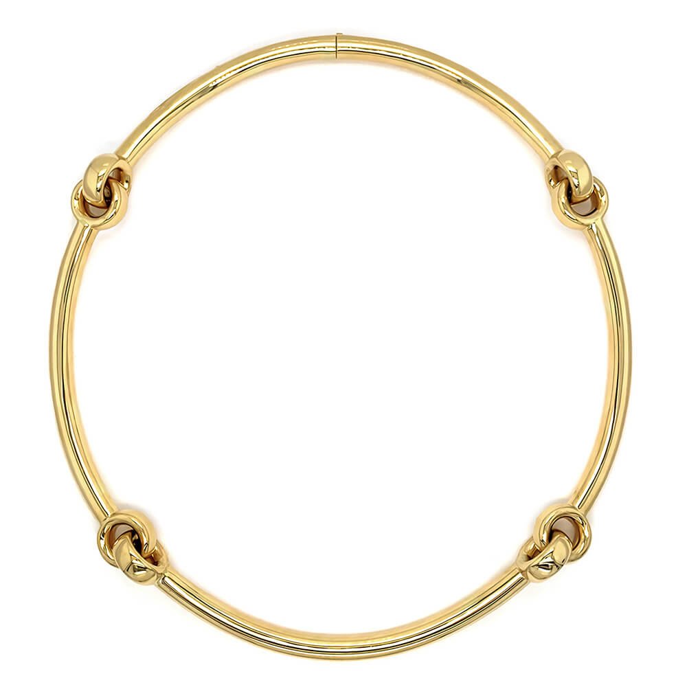 A polished 18k yellow gold necklace with four decorative knot-like accents spaced evenly around the circular band, shown on a plain white background.