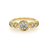 A golden 18k yellow gold bezel set diamond band ring with multiple small clear diamonds around the main large diamond.