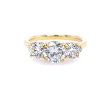 An 18k yellow gold three stone round diamond ring with a gold band and a central diamond surrounded by smaller round diamonds.