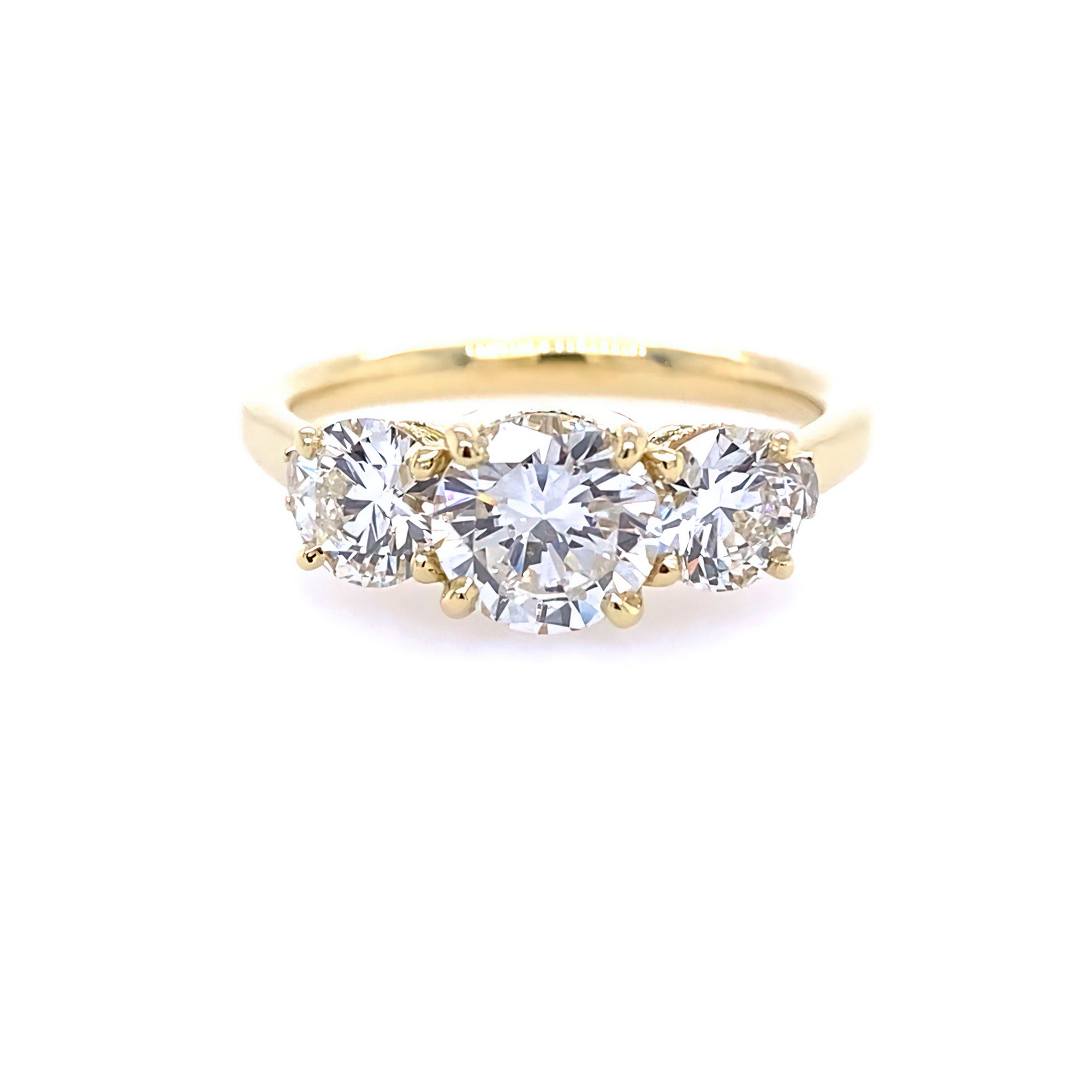 An 18k yellow gold three stone round diamond ring with a gold band and a central diamond surrounded by smaller round diamonds.