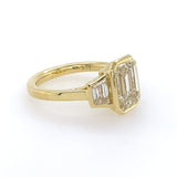 Side View 18k yellow gold bezel set emerald cut engagement ring with trapezoid side stones 