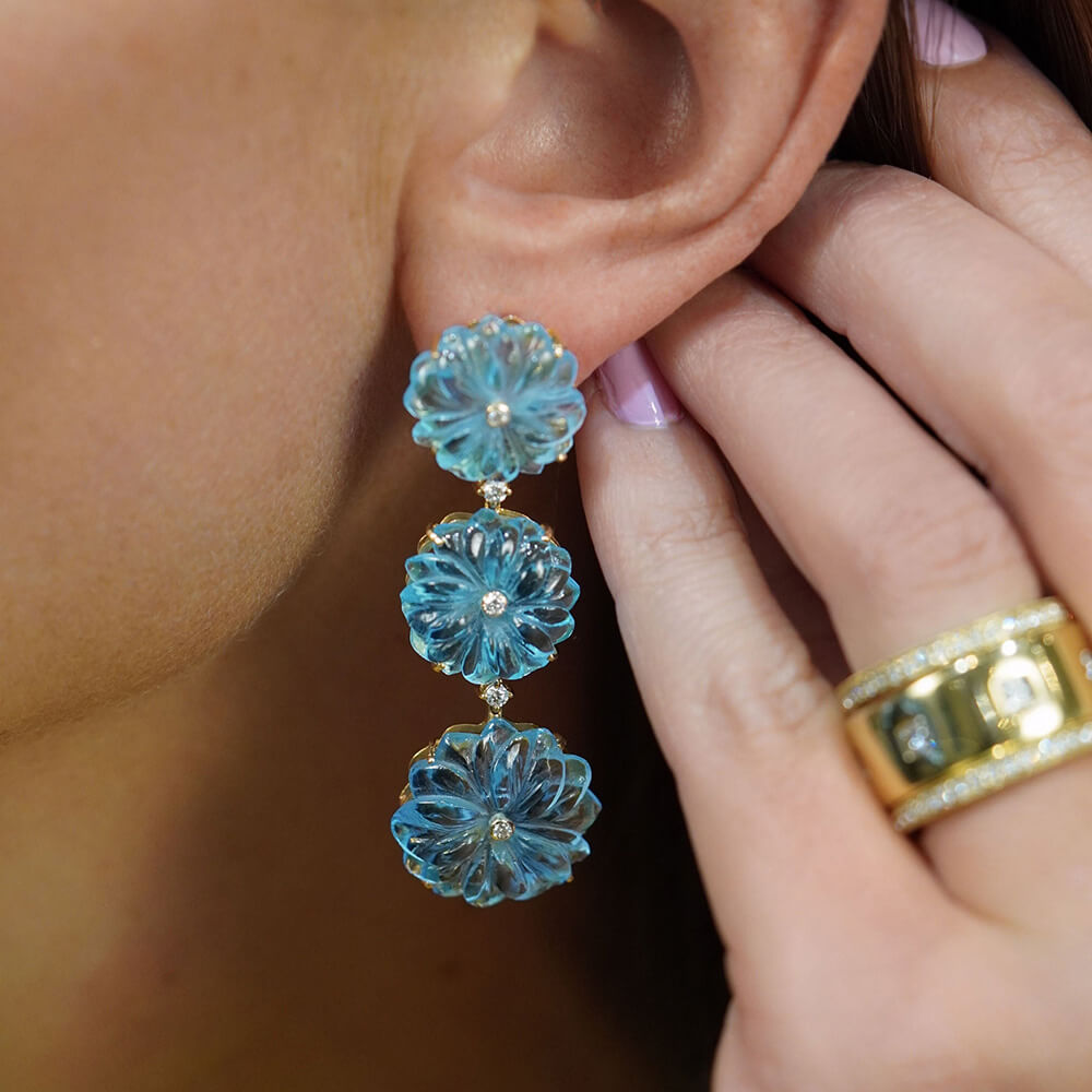 Close-up of a woman wearing blue topaz flower dangle earrings 