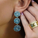 Close-up of a woman wearing blue topaz flower dangle earrings 