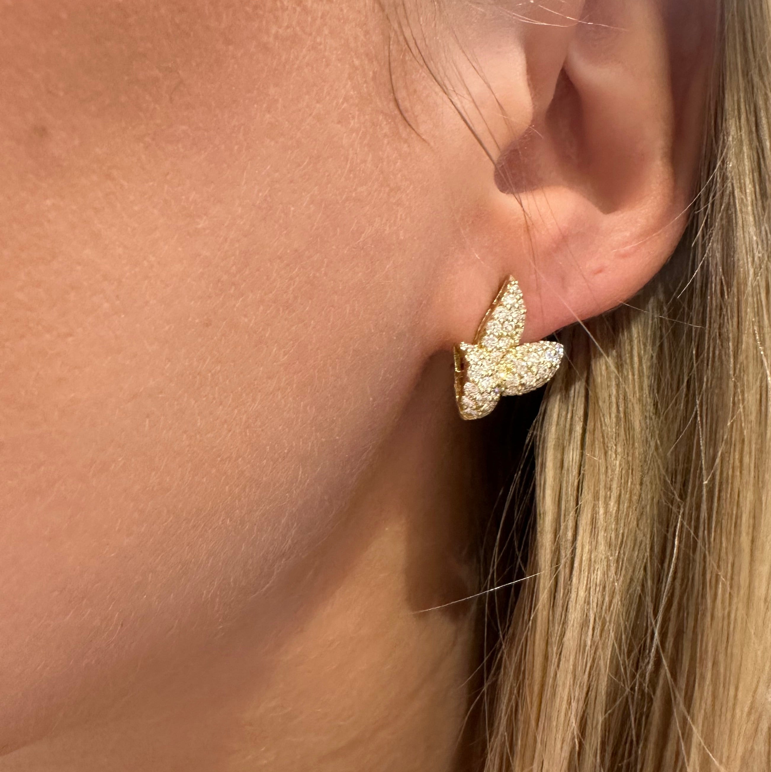 Close-up of a woman's ear with an 18k gold diamond leaf earring
