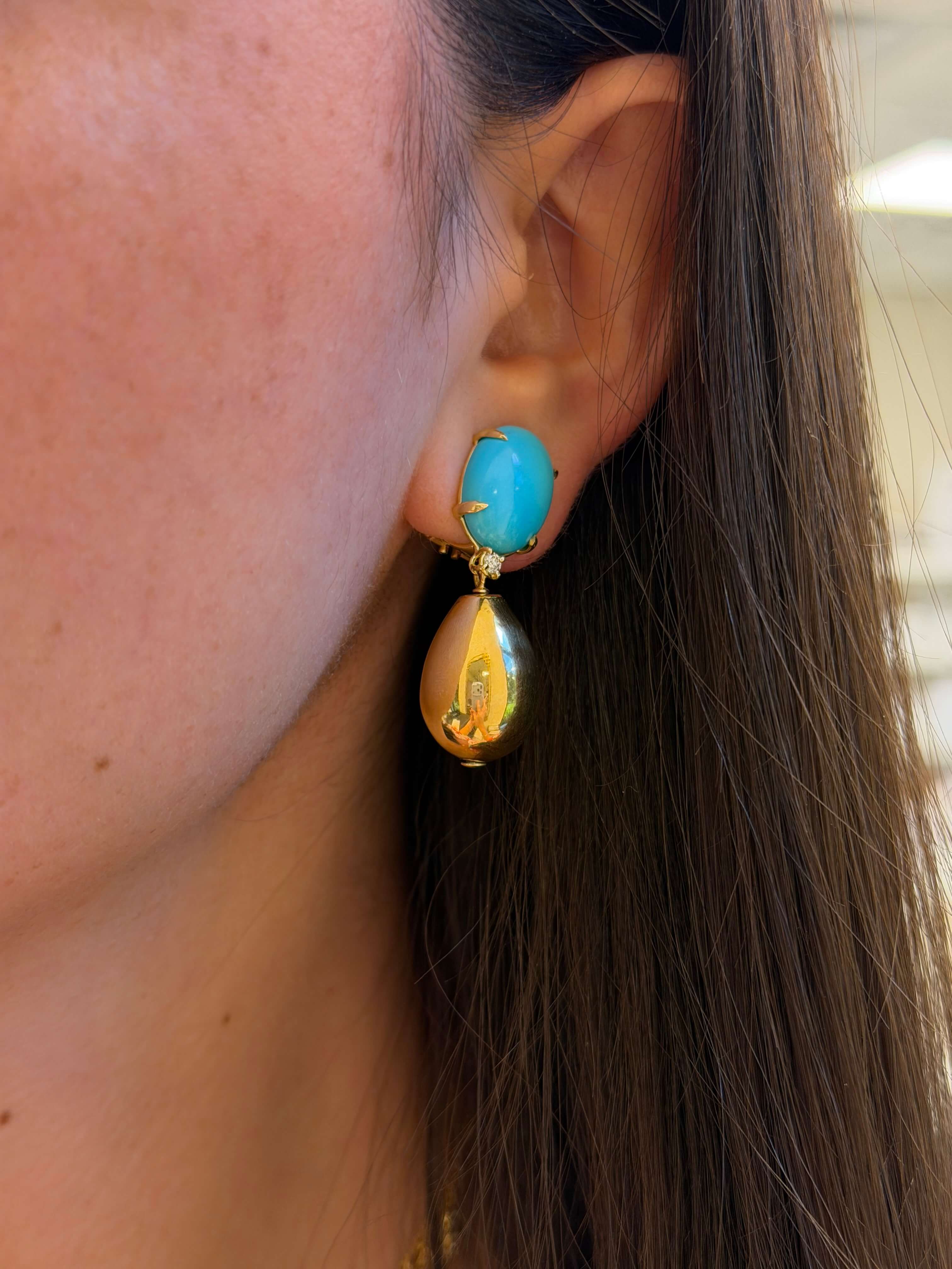 Close-up of a turquoise earring on an ear with blurred background