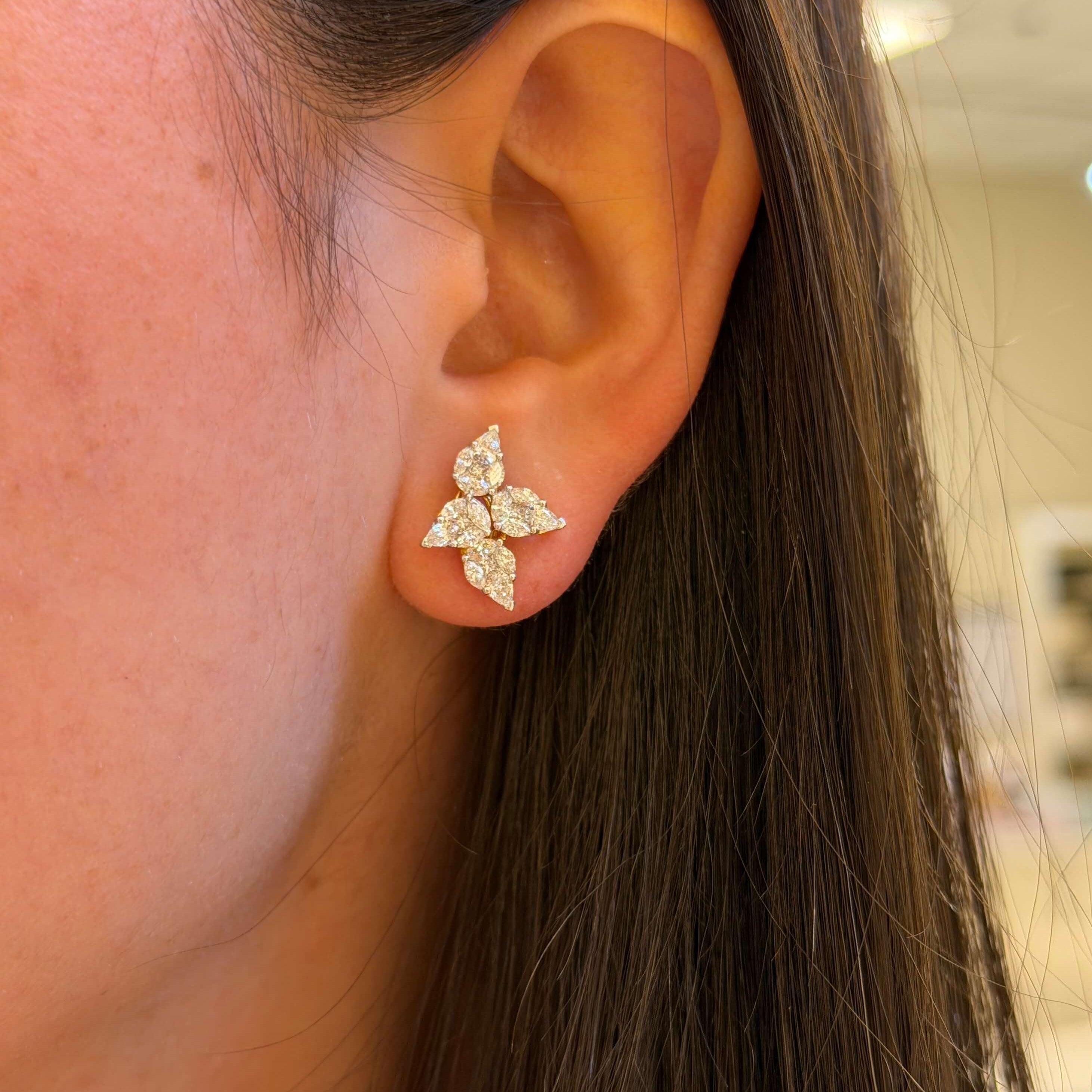 Close-up of an ear wearing a diamond earring with a blurred background