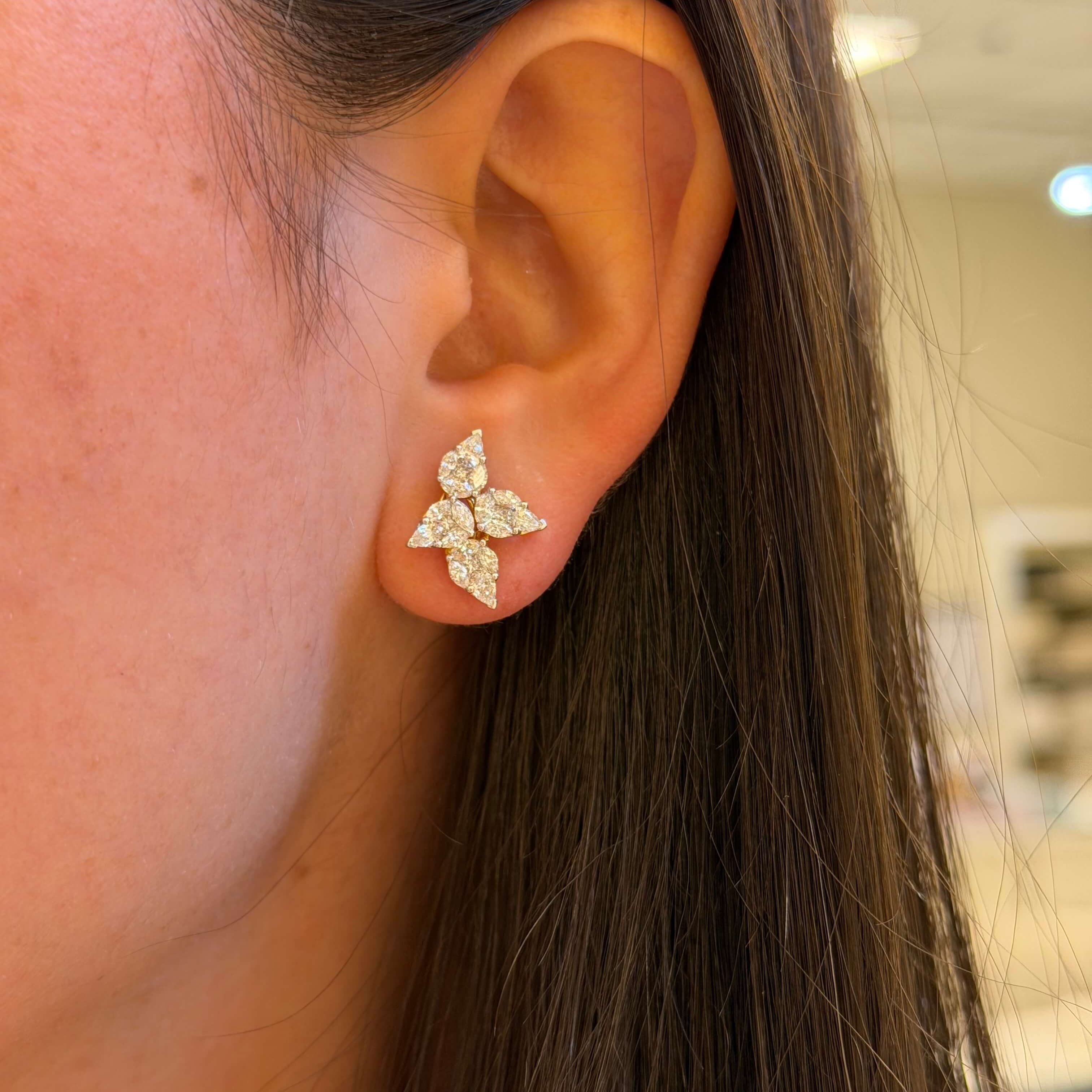 Close-up of an ear wearing a diamond earring with a blurred background