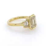 Side View 18k yellow gold bezel set emerald cut engagement ring with trapezoids side stones 